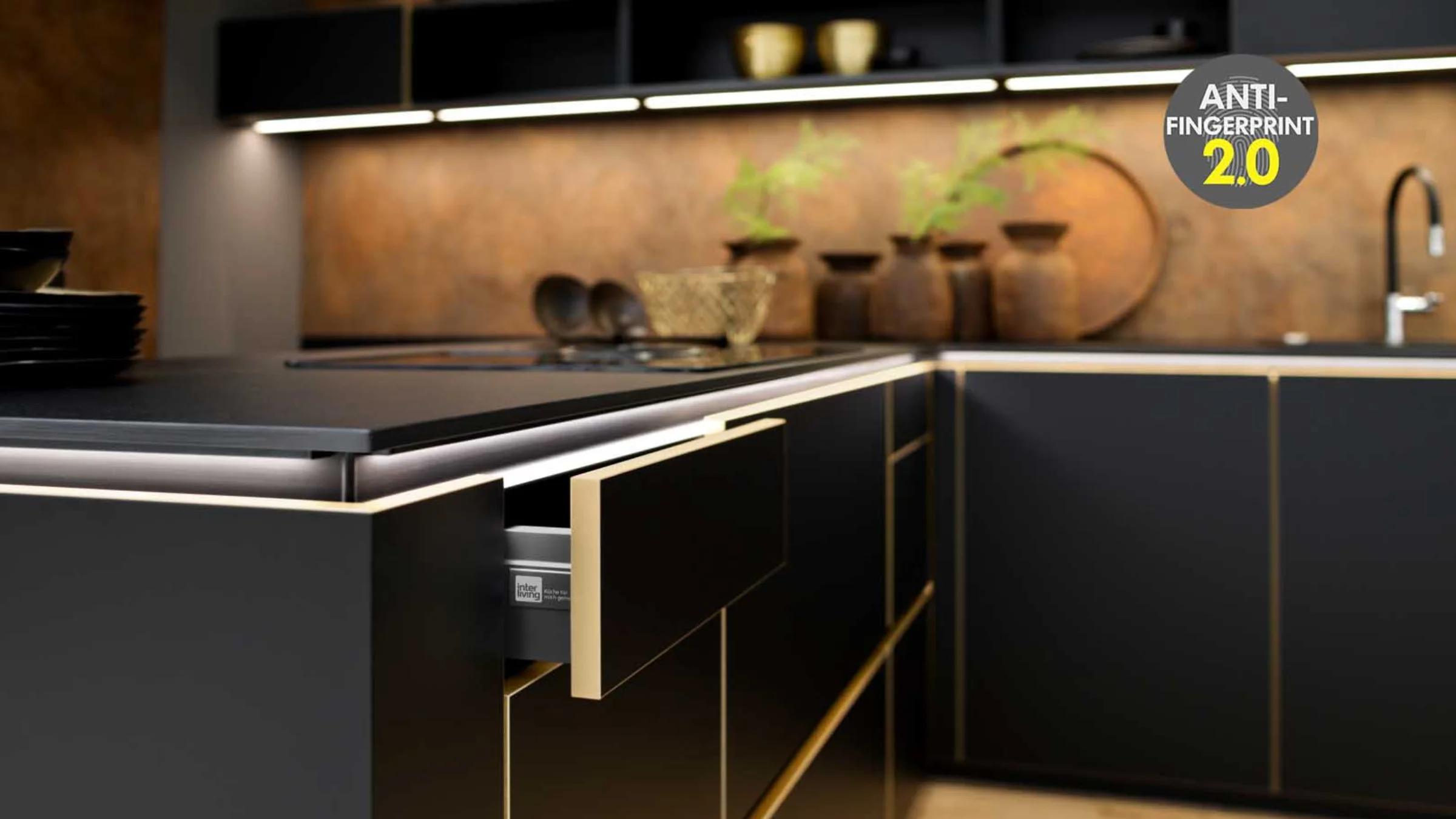 Moderne cucine Nolte Front FLAIR in nero opaco con eleganti bordi in ottone, abbinate a pannelli posteriori con illuminazione calda e piani di lavoro scuri.