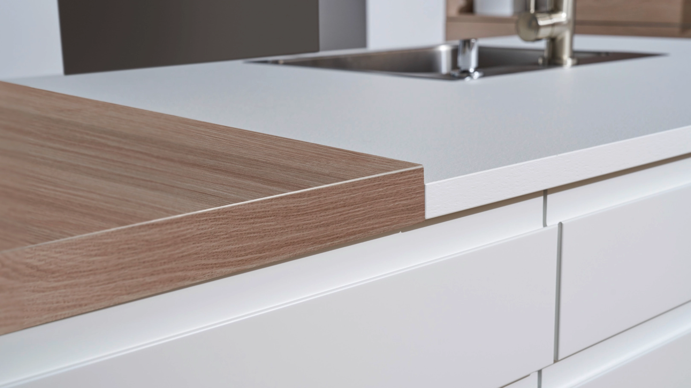 Una barra de cocina moderna con superficies de madera y blancas de Nolte Cocina.