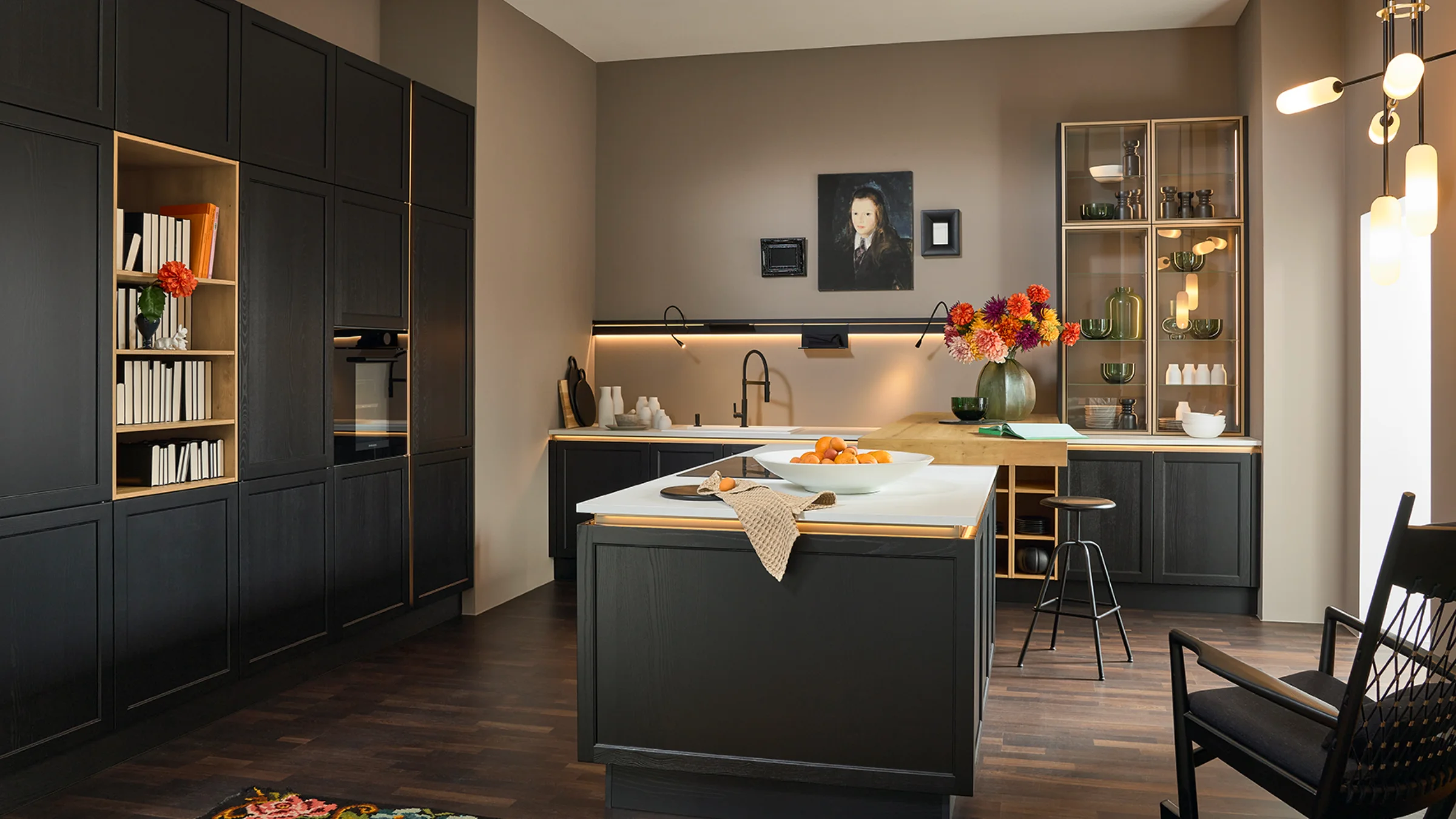 A modern kitchen with dark cabinets and a central island by Nolte Kitchen.