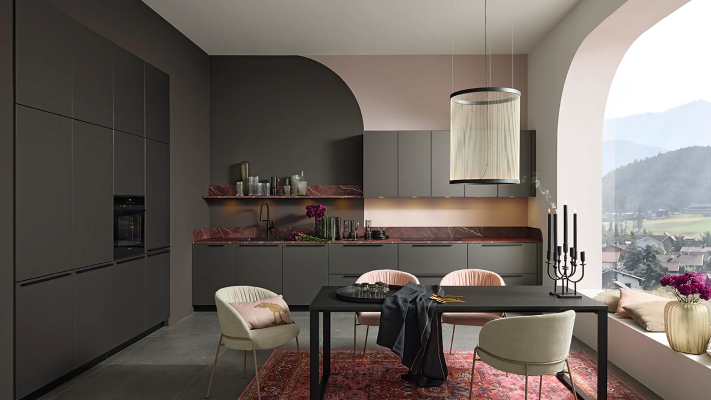 Modern kitchen with PEARL front in Umbra metallic from Nolte Küchen – featuring black handles, a red marble worktop, elegant beige tones and a large window with a mountain view.