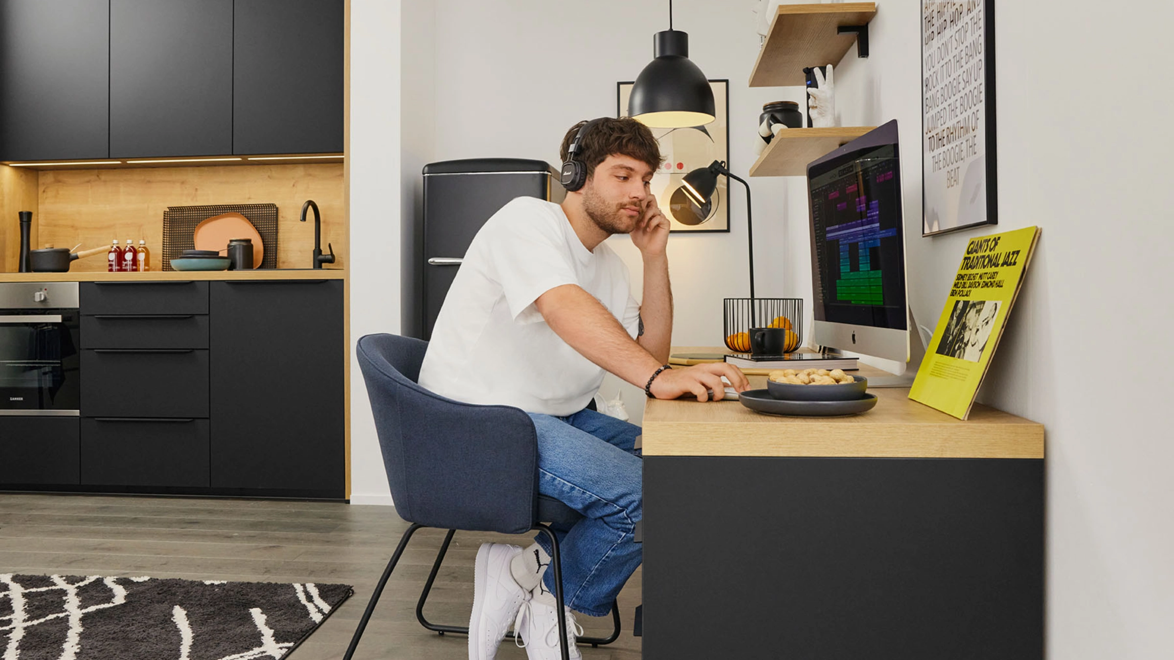 A man works at a desk with a computer in a modern Nolte Kitchen kitchen.