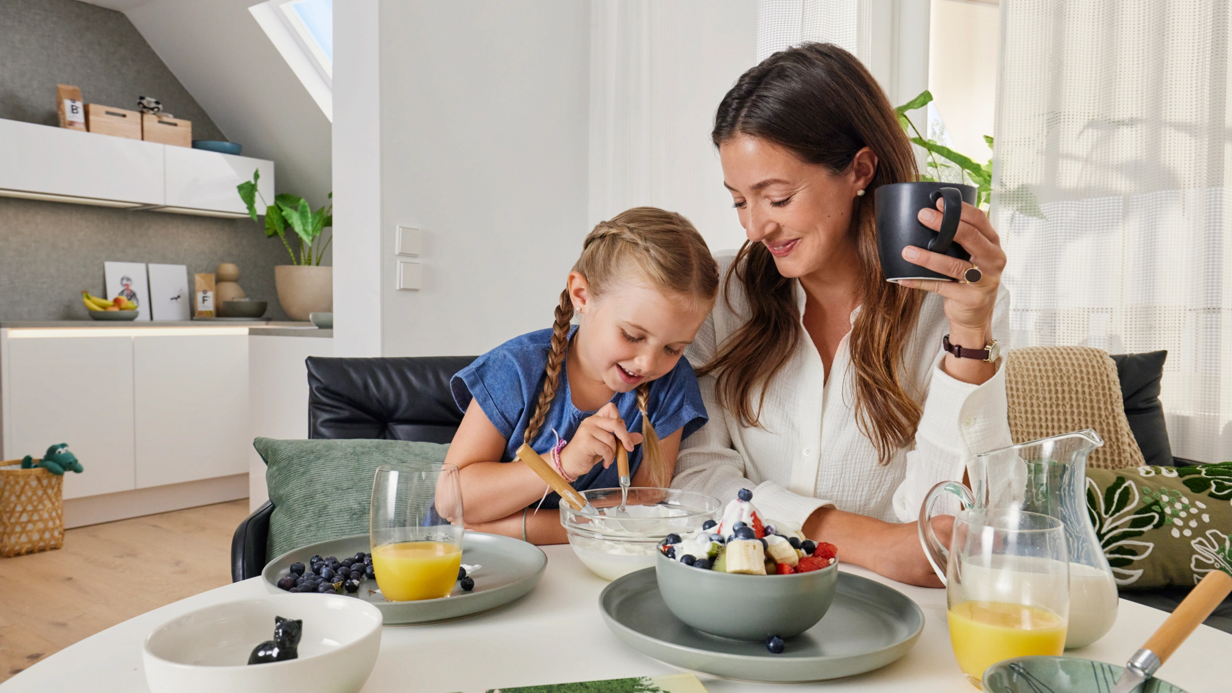 Une mère et sa fille prennent le petit-déjeuner ensemble dans une cuisine moderne de Nolte Kitchen.
