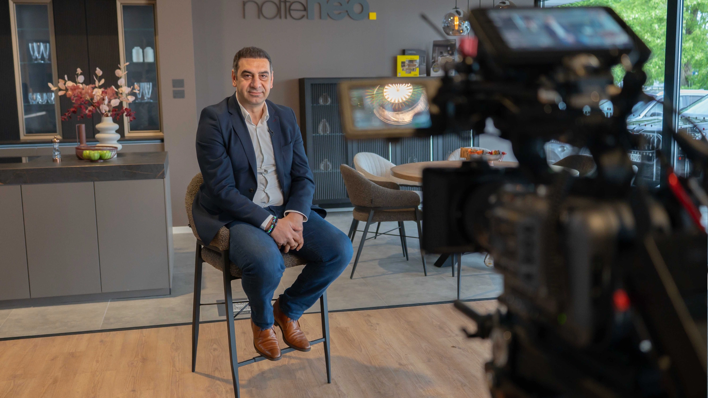 Un homme est assis sur un tabouret dans une cuisine moderne conçue par NolteNeo.