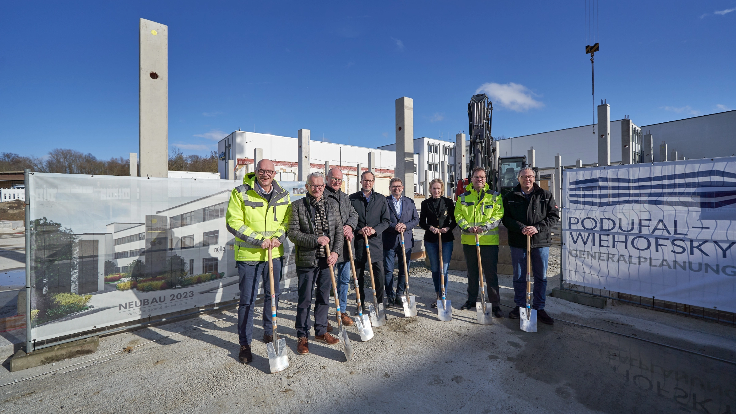 Un gruppo di otto persone con pale in un cantiere sotto il sole.