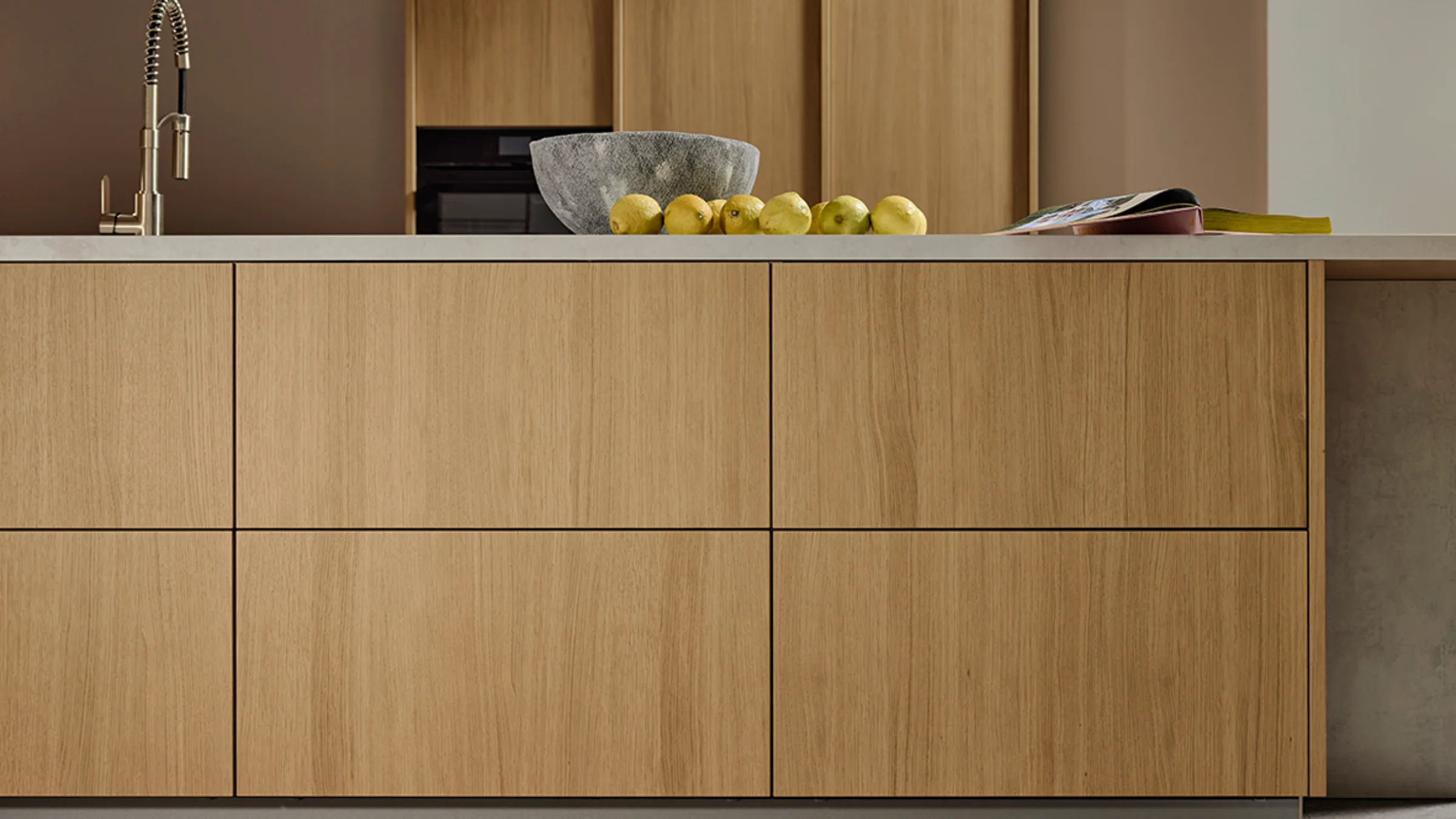 Frontansicht der Kücheninsel in Eiche Bianco mit minimalistischen Linien und integrierter Spüle. Natürliche Holzoptik und hochwertige Verarbeitung der nolteneo FLAT Front.