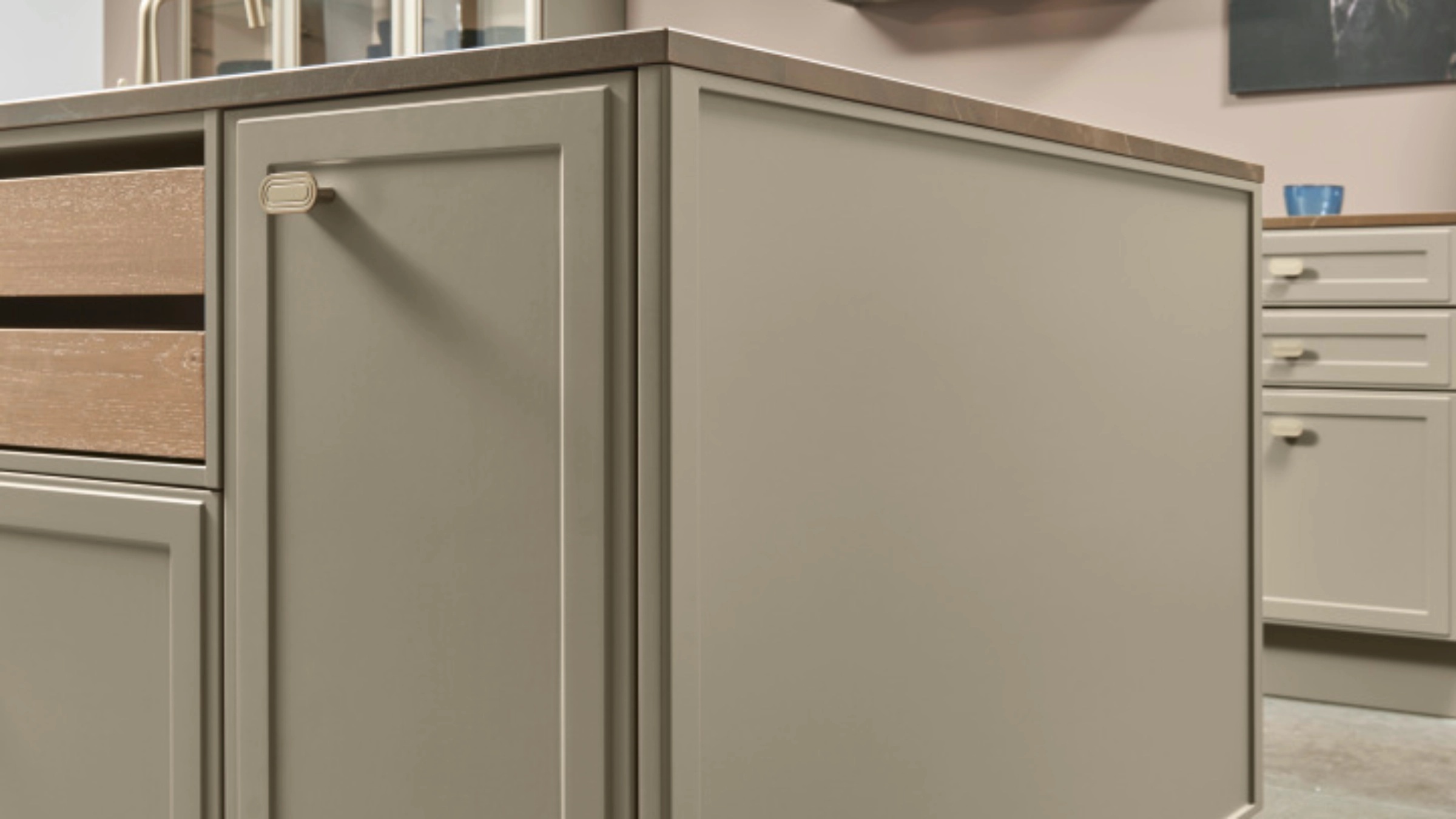Cuisine moderne avec îlot et armoires beiges, conçue par Nolte Kitchen.