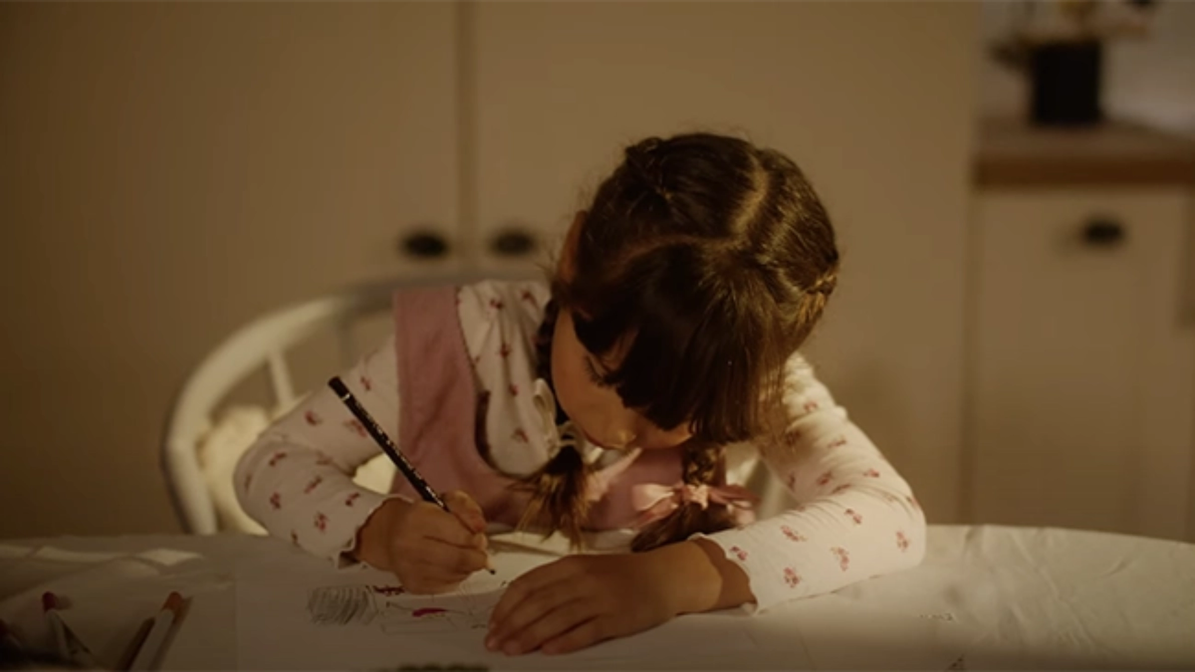 Un enfant dessine concentré à une table dans un cadre chaleureux.