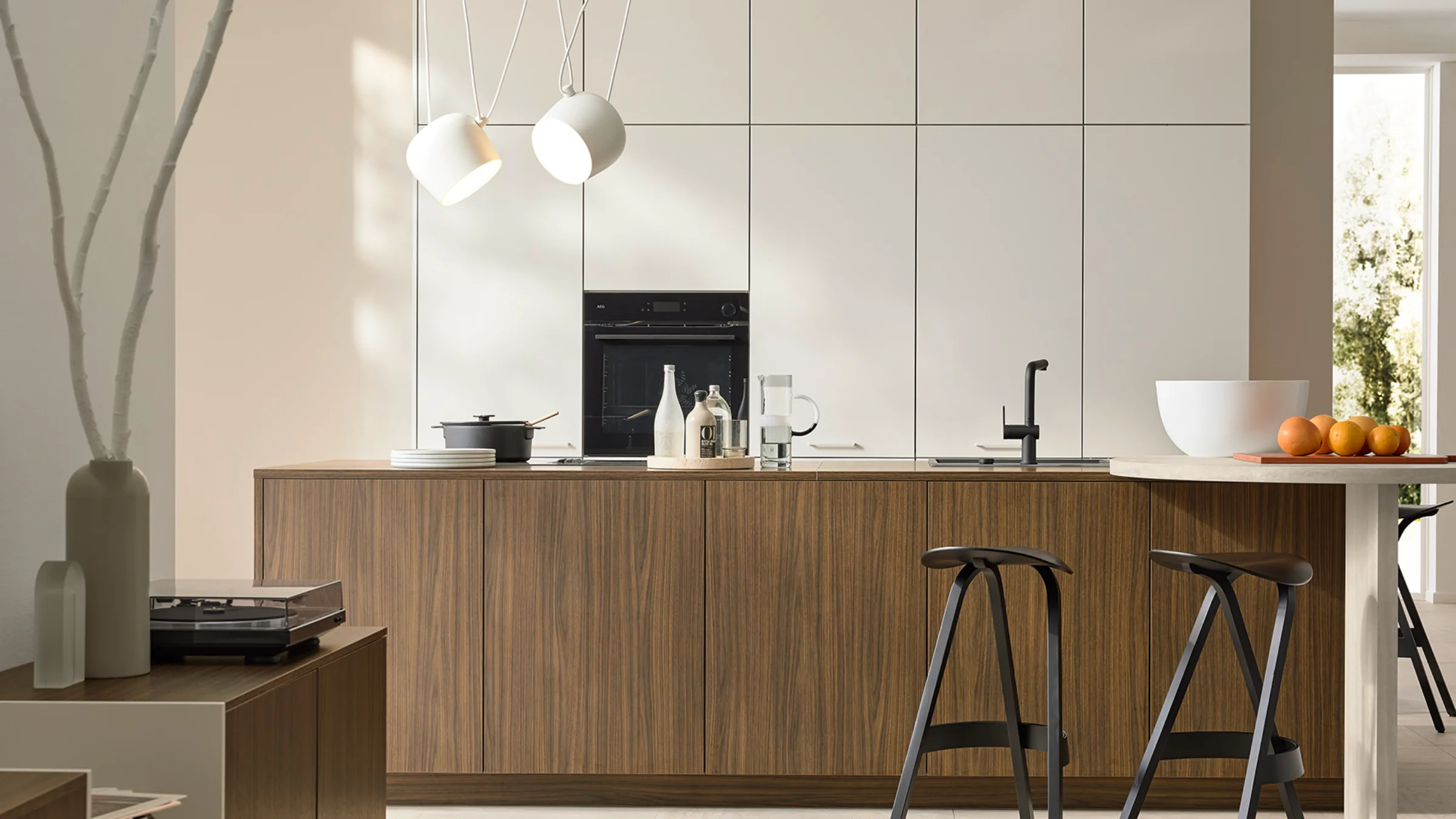 Una cocina moderna con frentes de madera y lámparas colgantes. Nolte Küchen.