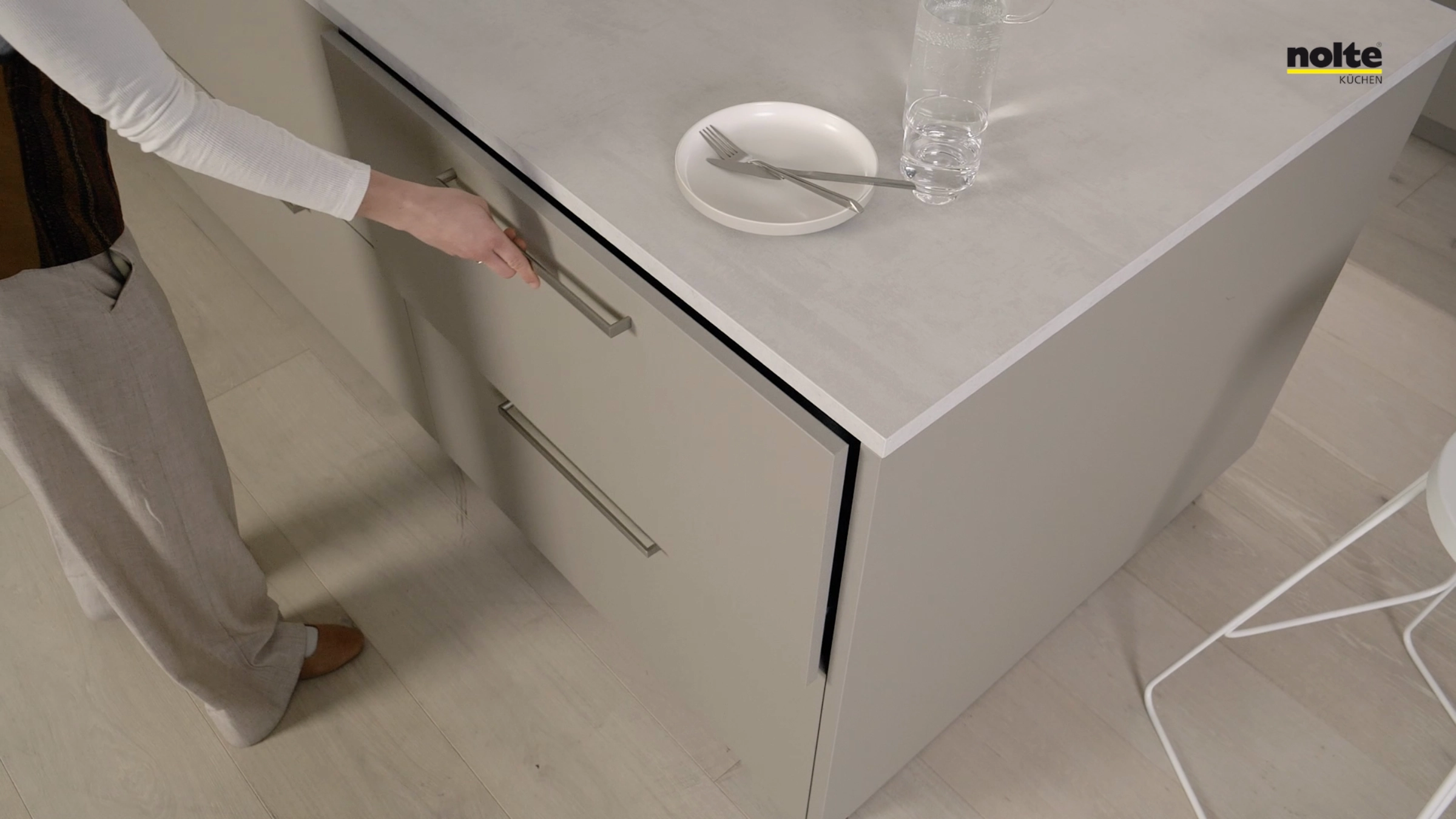 Eine Person öffnet eine Schublade in einer modernen Küche von Nolte Küchen.