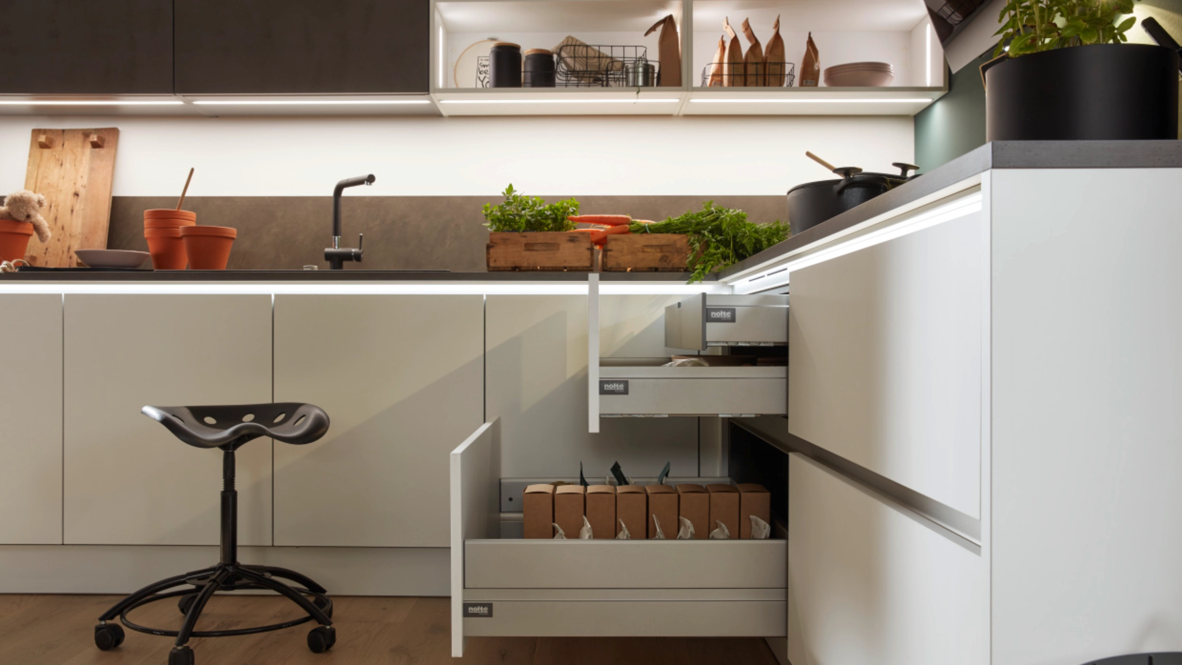 A modern kitchen with open drawers and herbs on the countertop, Nolte Kitchen.