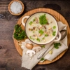 Une assiette de soupe aux champignons avec du persil et des champignons frais sur une table en bois.