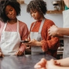 Twee mensen met schorten gebruiken een tablet in een moderne keuken, Nolte Kitchen.