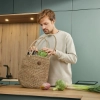 Een man staat in een moderne Nolte-keuken en legt boodschappen uit een juten tas op het aanrecht.