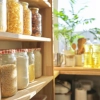 Étagères de cuisine avec aliments au soleil, plantes et ustensiles en arrière-plan. Nolte Kitchen.