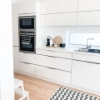 Cuisine moderne et lumineuse avec armoires blanches et tapis, élégamment conçue par Nolte Kitchen.