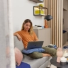 Donna seduta su un divano con laptop in un soggiorno moderno. Nolte Living.