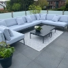 Une terrasse moderne avec canapé gris et table, entourée de plantes.