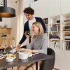 Un couple savoure un repas dans un espace moderne avec bibliothèque et cuisine, Nolte Living.
