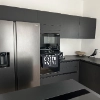 Une cuisine moderne avec des armoires noires et des appareils en acier inoxydable, assortie à Nolte Kitchen.