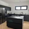 Cuisine moderne avec îlot noir et appareils, conçue par Nolte Kitchen.