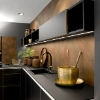 Cuisine moderne avec armoires noires et accents dorés, décorée de plantes. Nolte Kitchen.