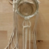 Un verre décoré avec des cordes en macramé sur une table en bois.