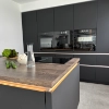 A modern kitchen with dark cabinets and an island, stylishly designed by Nolte Kitchen.