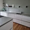 Eine moderne Küche mit weißen Schränken und Holzfußboden, präsentiert von Nolte Küchen.