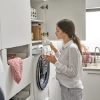 Une femme dans une buanderie moderne Nolte utilise une machine à laver.