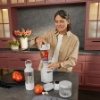 Une femme prépare un smoothie dans une cuisine moderne avec des placards rouges. Nolte Kitchen.