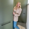 Une femme sourit dans une buanderie avec des placards verts. Buanderies Nolte.