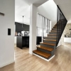 Cuisine moderne avec mur noir et îlot, escalier en bois à côté. Nolte Kitchen.