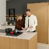 Un couple regarde un livre de cuisine dans une cuisine moderne avec des détails en bois, Nolte Kitchen.
