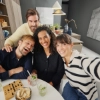 Eine Gruppe von Menschen sitzt lächelnd in einer modernen Küche. Nolte Küchen.
