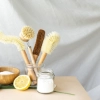 Sur une table, des brosses de nettoyage naturelles, un demi-citron et du sel.