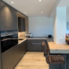 Cucina moderna con armadi scuri e accenti in legno, arredata da Nolte Kitchen.