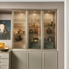 Un élégant buffet avec vitrine en verre, décoré de vaisselle et d'art, par Nolte Living.