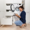 Un homme utilise une machine à laver dans une buanderie moderne Nolte.