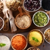 Divers bols de riz, lentilles et haricots disposés sur une table en bois.