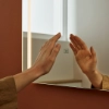 Een hand raakt een verlichte spiegel aan in een stijlvol Nolte SPA-badkamer.
