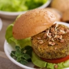 Un burger végétarien avec salade et pousses est sur une assiette.