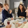 Quatre personnes assises joyeusement autour d'une table avec boissons et snacks dans un salon moderne. Nolte Living.
