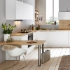 Cuisine lumineuse avec armoires blanches et détails en bois, table et chaise à gauche, fenêtre en arrière-plan. Nolte Kitchen.