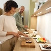 Une femme et un homme préparent des sushis dans une cuisine moderne de Nolte Kitchen.