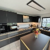 Cucina moderna con mobili neri e illuminazione LED, al centro un tavolo con bouquet. Nolte Kitchen.