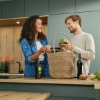 Un couple déballe des légumes dans une cuisine moderne Nolte.