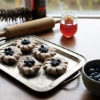 Sur une table, des pâtisseries aux myrtilles, un verre de jus et un bol de myrtilles.