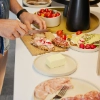 Eine Person bereitet Sandwiches mit frischen Zutaten in einer modernen Küche von Nolte Küchen zu.