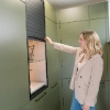 Une femme ouvre un placard dans une buanderie moderne conçue par Nolte Utility Rooms.