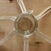 Un verre est maintenu par des cordes en macramé, étalées sur une table en bois.